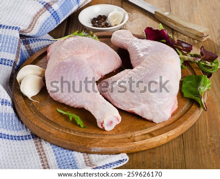 Fresh raw chicken legs on  a cutting board.