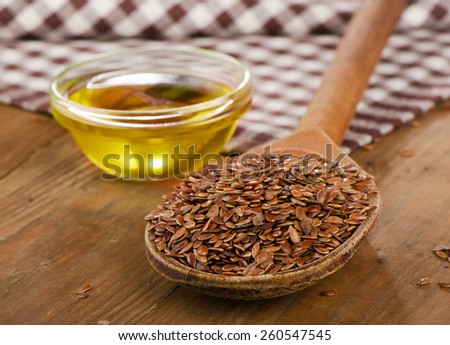 Brown flax seeds on a spoon and flaxseed oil  on wooden table.