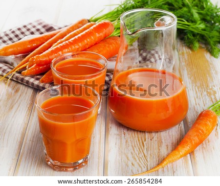 Fresh carrot juice and organic raw carrots on a wooden table. Selective focus
