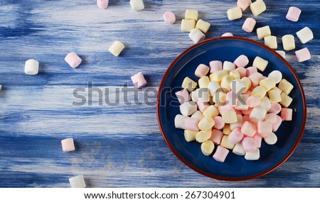 Colorful small marshmallows on  blue wooden background. Top view