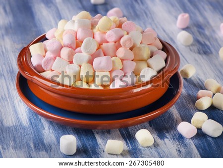Colorful small marshmallows on a blue wooden background. Selective focus