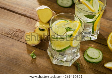 Fresh water with lemon, mint , ginger and cucumber  on a wooden background. Selective focus