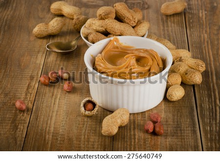Peanut butter with peanuts on a rustic wooden table.  Shallow dof.
