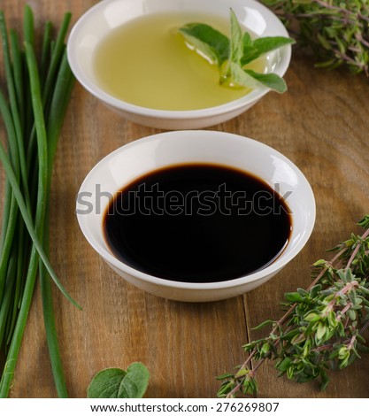 Olive oil, balsamic vinegar and herbs  on a vintage wood background