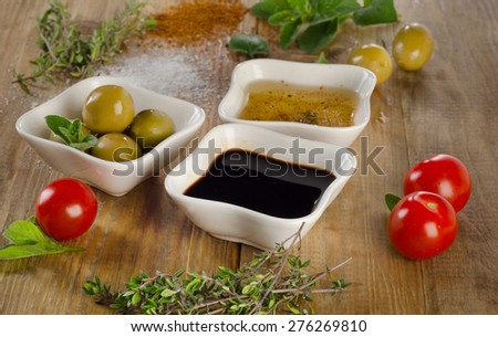 Dressing ingredients on a wooden background. Olive oil, balsamic vinegar, herbs, salt and pepper. Selective focus
