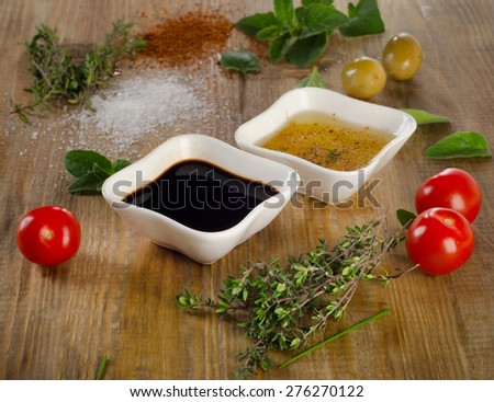 Dressing ingredients on a rustic background. Olive oil, balsamic vinegar, herbs, salt and pepper. Selective focus