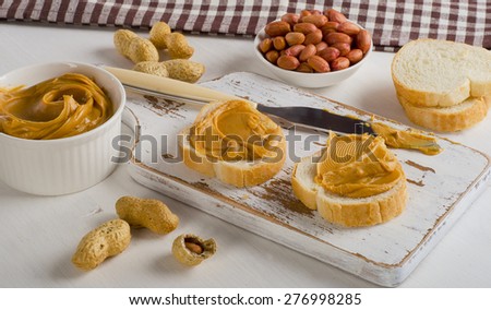 Toast with Peanut butter  and peanuts on  white wooden board.
