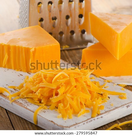 Grated Cheddar Cheese on  Cutting Board. Selective focus