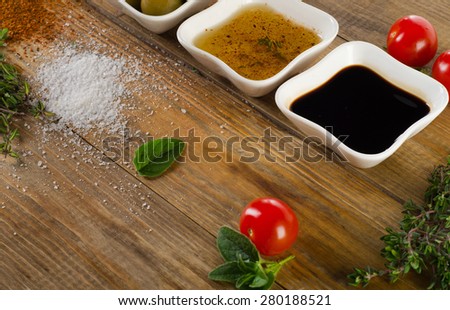Dressing ingredients on  rustic wooden background. Olive oil, balsamic vinegar, herbs, salt and pepper. Selective focus