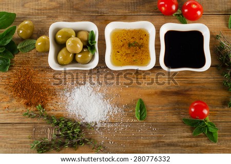 Dressing ingredients on  rustic wooden background. Olive oil, balsamic vinegar, herbs, salt and pepper. Top view