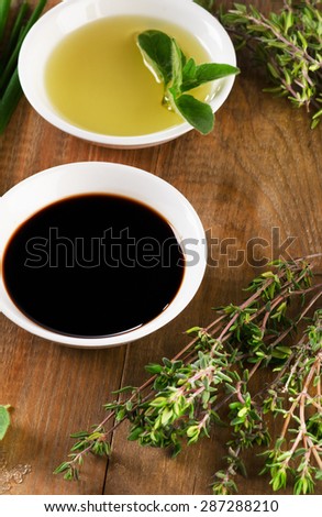 Olive oil, balsamic vinegar and herbs  on vintage wood background from above.