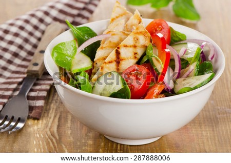 Salad with grilled chicken in  white bowl. Selective focus