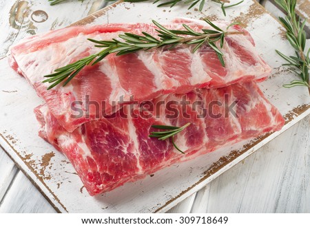 Raw ribs with a rosemary on a white wooden table