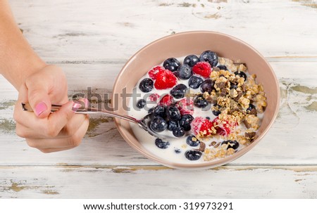 Woman Hand holding a spoon filled with  muesli and berries. Top view