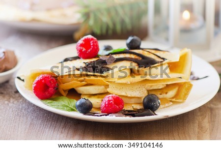 Christmas sweet breakfast. Crepes with chocolate cream and fresh berries. Selective focus