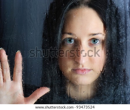 young girl behind wet window with a rain drops