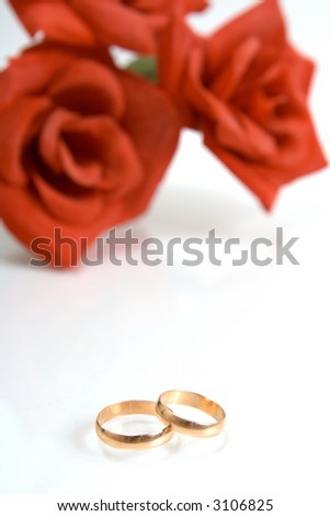 stock photo Two wedding rings and red rose at the background
