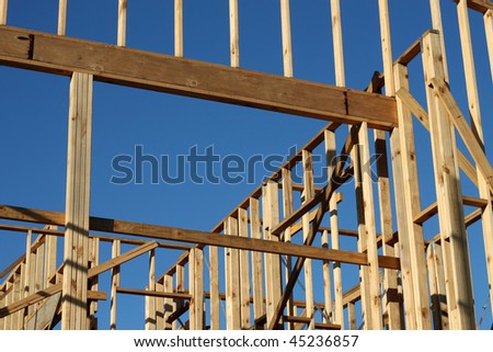 A home under construction with the focus on the window frame, against a blue sky.