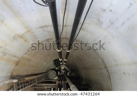Service Tunnel featuring pipes and cables, carrying electricity, gas and water.  Infrastructure serviced by a ladder.