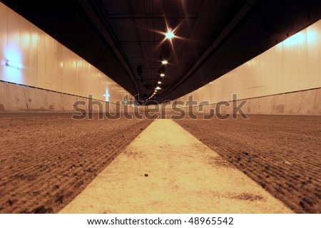 Middle of road inside an empty road tunnel with emphasis on the line marking ahead.