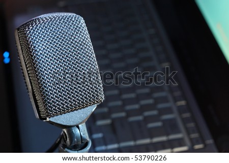 Retro microphone in focus, with laptop soft background.  Plenty of copy space to list your website, podcast or audio stream.