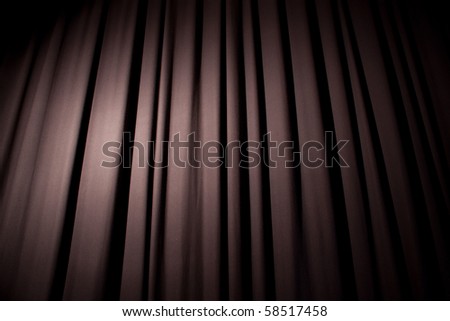 Heavy dark blue curtain with background texture and copy space.  Angled view.  Spotlight creating natural vignette.