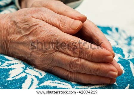 pair of hands of old woman in prayer on knees