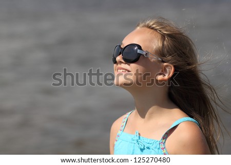 portrait of a child girl wearing sunglasses with developing hair in the wind
