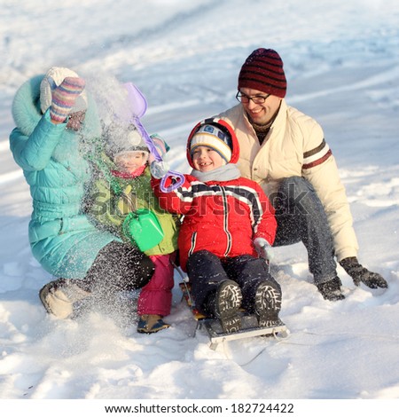 A family of four has fun in the snow in winter