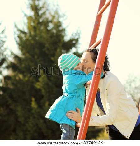 Beautiful young mother doing fitness with his little daughter at the playground