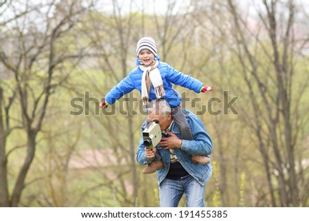 Grandfather and grandson indulge. Grandfather Carrying Grandson On His Shoulders. The grandfather makes movies on old movie camera.