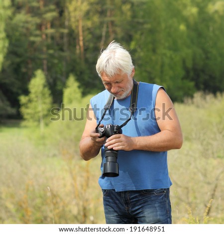 Old man with gray hair into the Wildlife. Old photographer enjoys traveling and photography