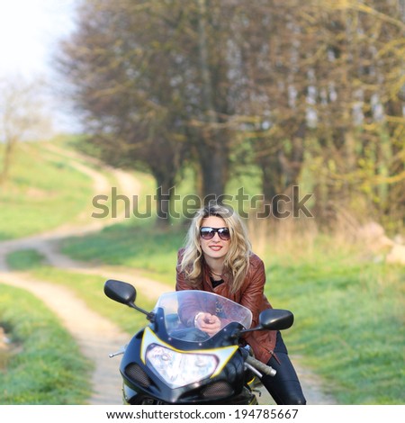Portrait of attractive girl on sports bike. Biker girl with sunglasses and motorcycle