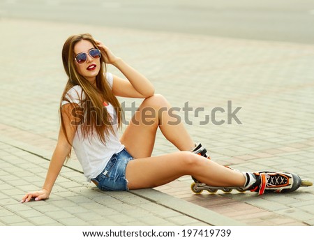 Beautiful girl sitting on the road in roller skates