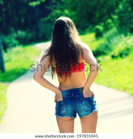 hot summer girl in sunglasses and denim shorts. view from the back