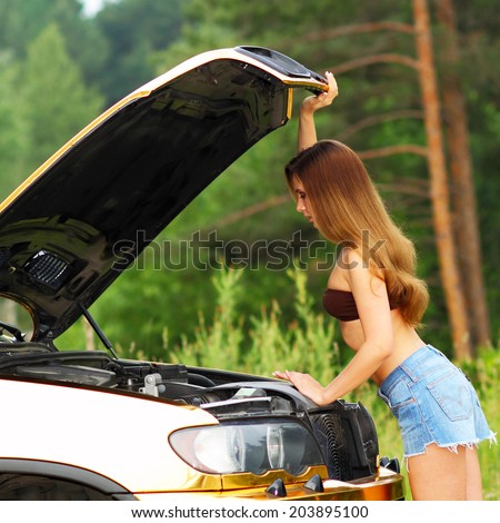 attractive girl in bikini looking under the hood of a car