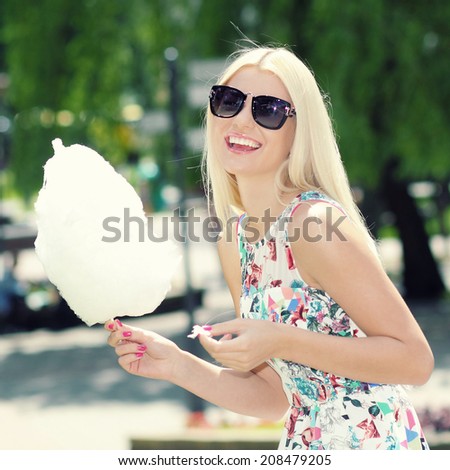 summer trendy girl in sunglasses having fun in the park and eating candy floss. Outdoors. Urban lifestyle shot.