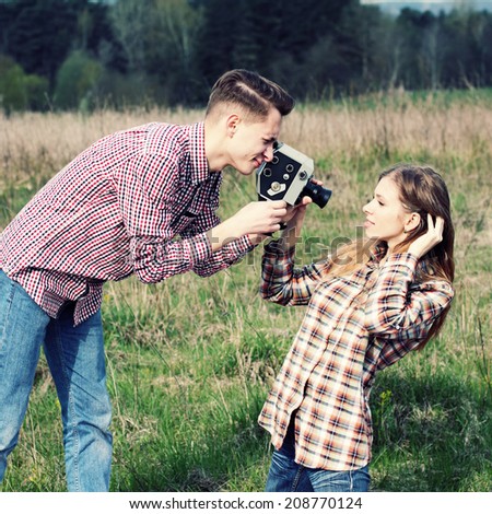 young hipster guy photographs the girl on a vintage camera. Young hipster couple on a picnic