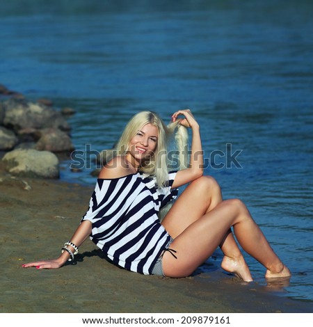 Fashionable beautiful blonde in a striped blouse enjoying on the beach