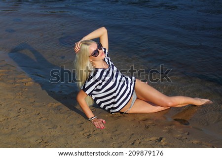 Fashionable beautiful blonde in a striped blouse enjoying on the beach