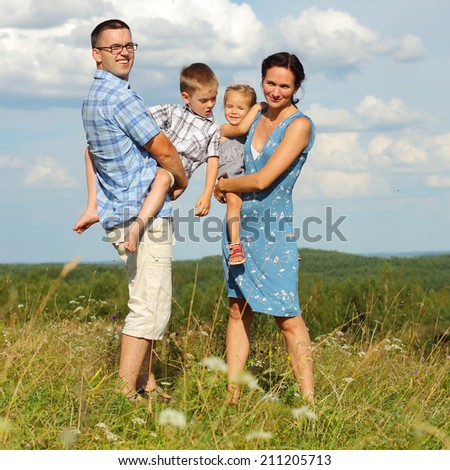 Family of four standing on a mountain on the background of clouds. Portrait of a happy family.