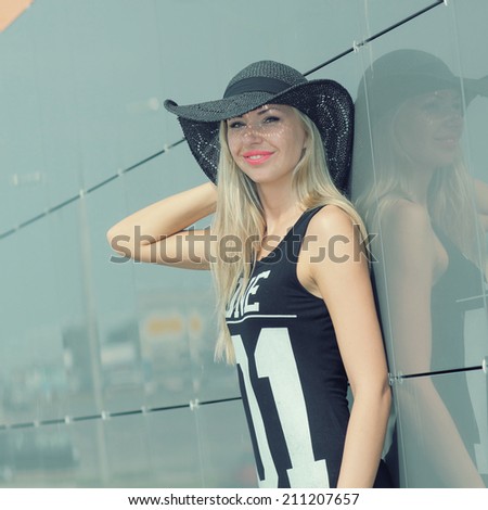 beautiful attractive trendy girl in long-skirted hat posing on the background wall mirror