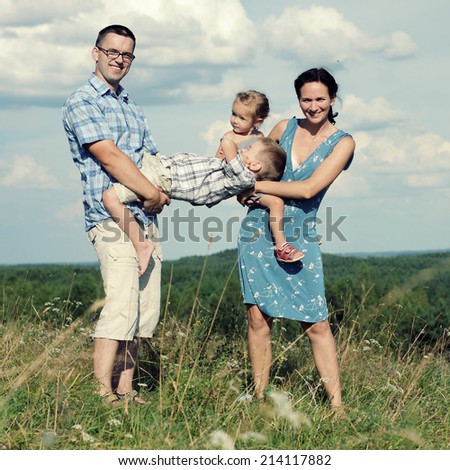happy young family of four having fun on the top of a hill on a background of clouds