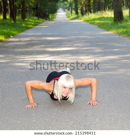 Fitness woman doing push-ups during outdoor cross training workout. Beautiful young and fit fitness sport model training outside in fall.