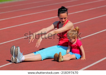 Mother and little daughter are engaged in running in the stadium. family doing fitness at the stadium