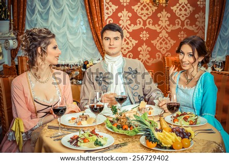 company in the historic vintage clothing have fun in a richly served restaurant. Retro company portrait. Romantic Beauty.Vintage Styled