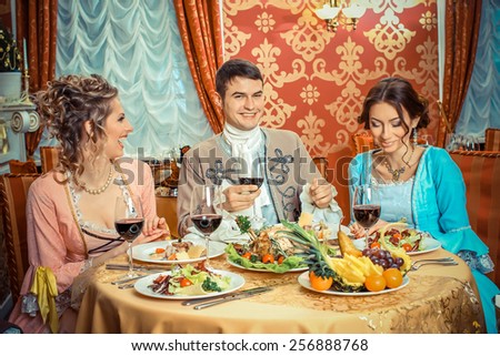 company in the historic vintage clothing have fun in a richly served restaurant. Retro company portrait. Romantic Beauty.Vintage Styled