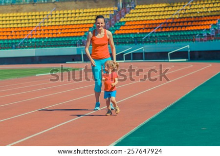 Mother & little daughter running around the stadium. Child runs away from mom at the stadium.