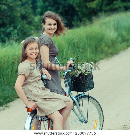 Two hipster girl friends on bicycle having fun. Outdoors, lifestyle. Teenage Girls On Bike