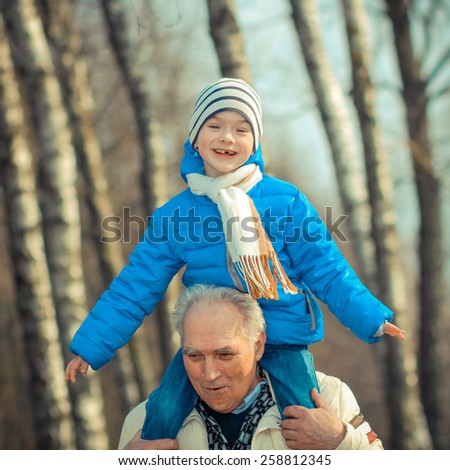 Grandfather and grandson indulge. Grandfather Carrying Grandson On His Shoulders. The grandfather makes movies on old movie camera.